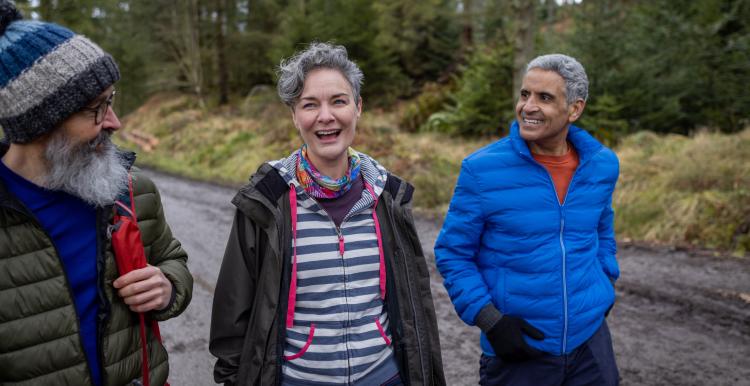 Group of three older people out walking in the woods.