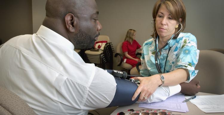 Black man having blood pressure taken by a female health professional