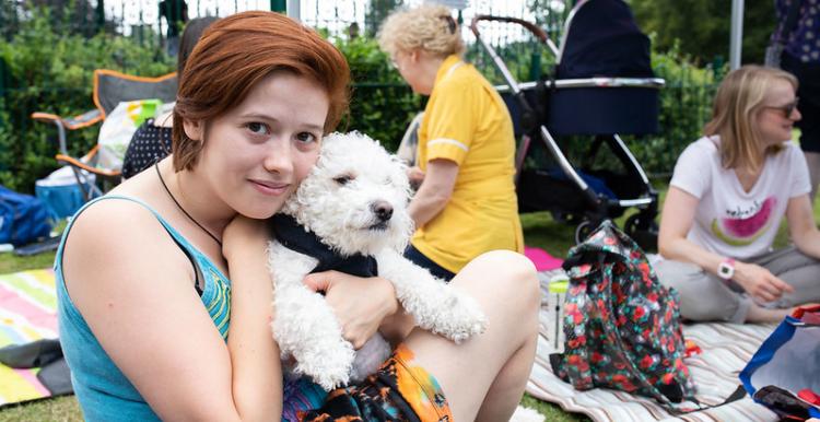 Female teenage sitting outside at a picnic cuddling a white dog