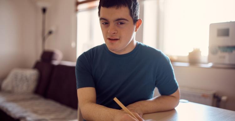 Young man with learning disabilities writing at a table