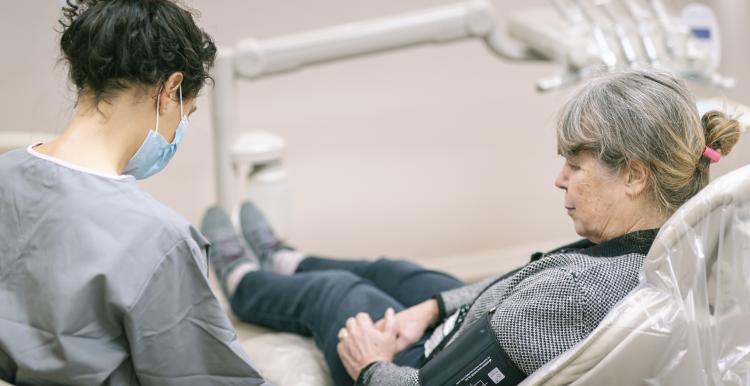 Woman sitting in a dentist's chair having her blood pressure taken by a dentist