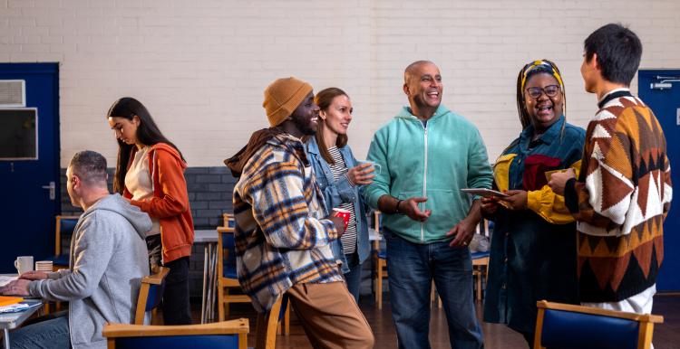 Diverse group of people standing and talking in a community hall