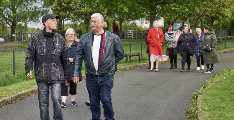 Group of people walking in a park range of ages and nationalities