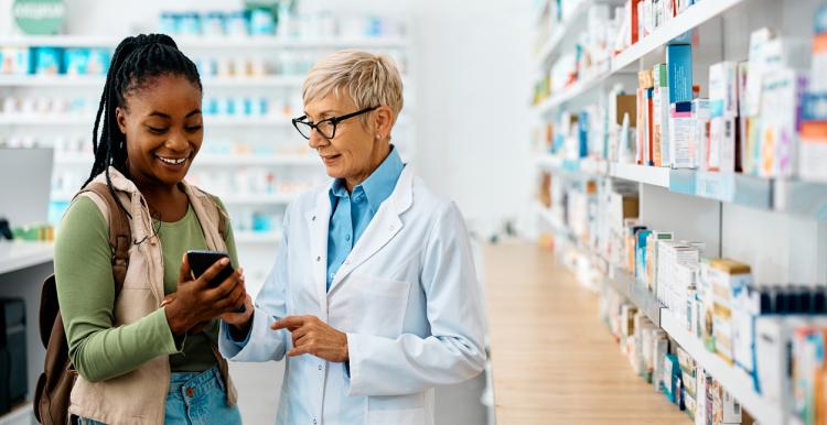 Female pharmacist talking to a young woman with pharmacy store in background