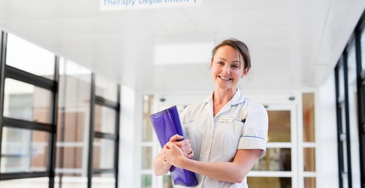 Woman in a nurses uniform stood in a hospital corridor