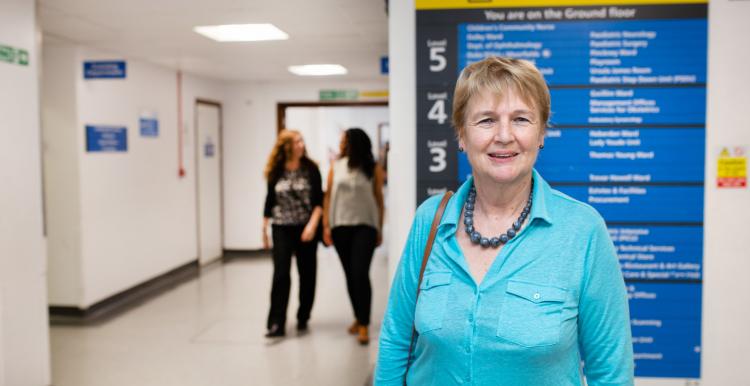 Woman standing infront of a hospital sign that shows all the different departments