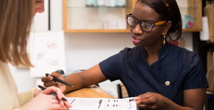 Receptionist talking through a patient how to complete a form