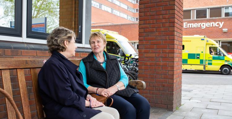 Two women sitting on a bench talking