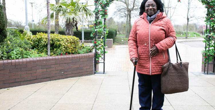 Picture of a lady using a walking stick standing outside
