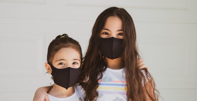 Two young children facing camera both wearing masks