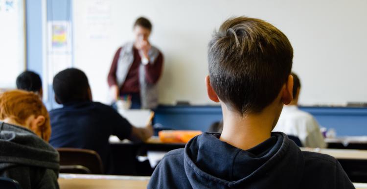 Rear view of young people sitting in a classroom at their desks