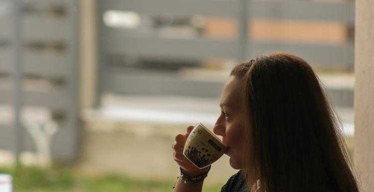 Woman drinking a cup of tea looking out the window at a garden