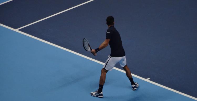 Image of a man playing tennis on a blue tennis court