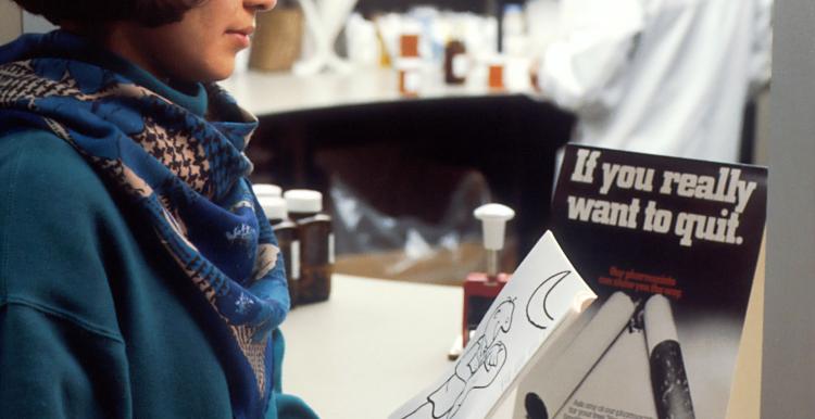 Person waiting at pharmacy with quit smoking sign on counter