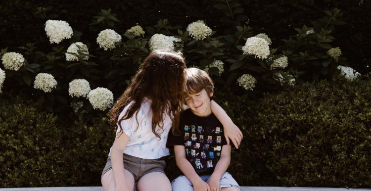 Young boy and girl outside hugging