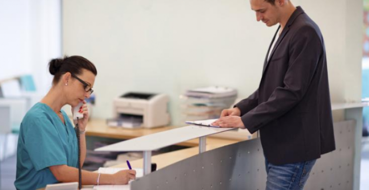 Female receptionist talking on the phone while patient waits