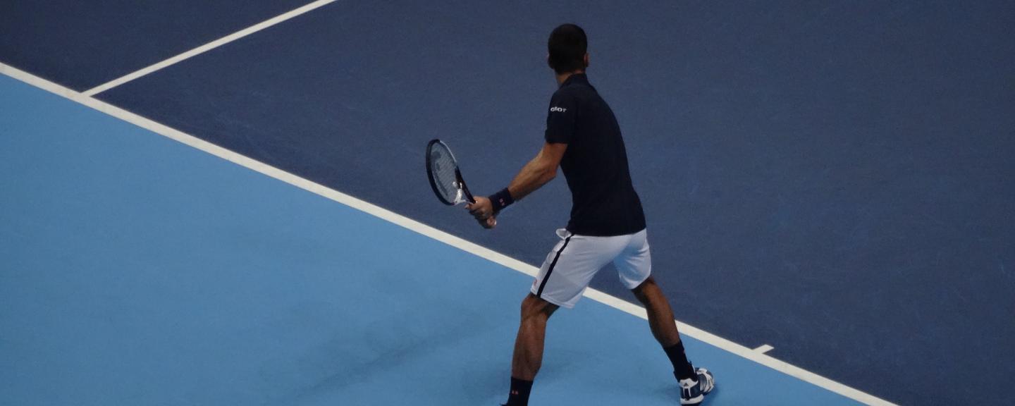 Image of a man playing tennis on a blue tennis court
