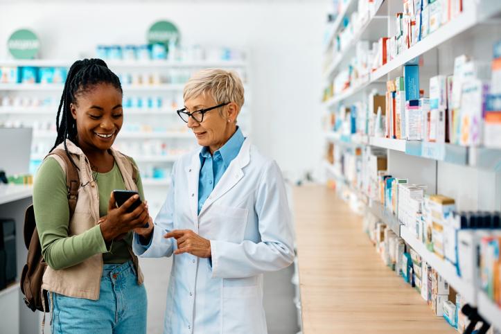 Female pharmacist talking to a young woman with pharmacy store in background