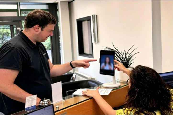 Deaf man points to a screen in a GP receptionist office