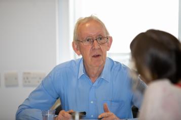 Elderly man speaking to a lady while sitting at a table