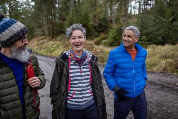 Group of three older people out walking in the woods.