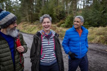 Group of three older people out walking in the woods.