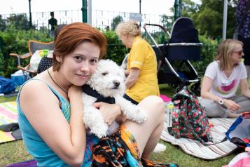 Female teenage sitting outside at a picnic cuddling a white dog