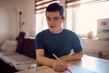 Young man with learning disabilities writing at a table