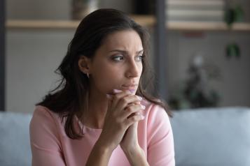 Middle-aged woman sitting on sofa staring out the window