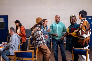 Diverse group of people standing and talking in a community hall