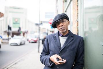 Man standing outside a shop leaning on the wall 