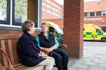 Two women sitting on a bench talking