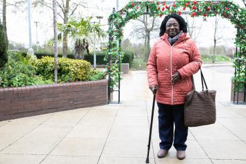 Picture of a lady using a walking stick standing outside