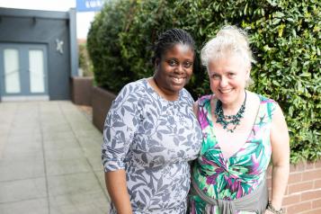 Two women standing closely together smiling at the camera