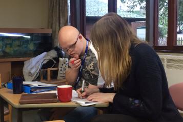 Alice sitting at a desk working with one of our volunteers