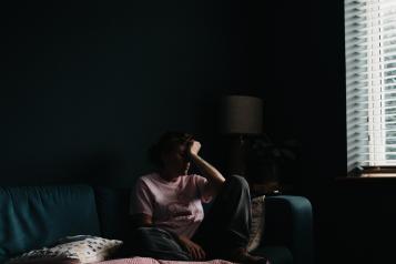 Person sitting on a couch in a dark room