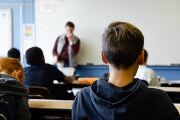 Rear view of young people sitting in a classroom at their desks