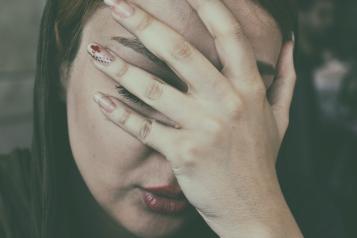 Close up photo of woman holding her head with one hand
