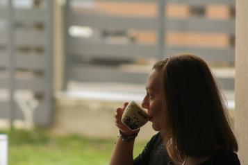 Woman drinking a cup of tea looking out the window at a garden