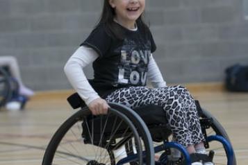 child smiling using a wheelchair