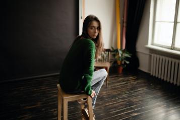 Young woman sitting on a stool in the middle of a room