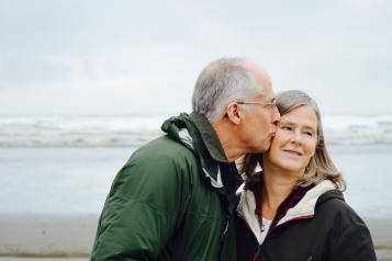 Older man kissing his female partner on the cheek at the beach