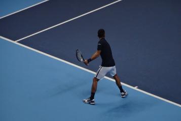 Image of a man playing tennis on a blue tennis court