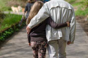 Older man with granddaughter walking down street