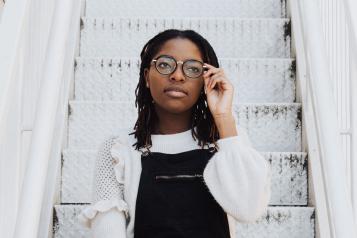 Young woman sitting on white metal stairs