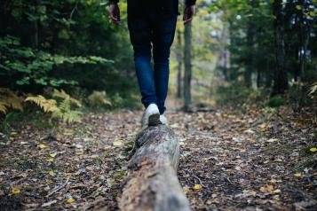 Person walking along a fallen log in the woods