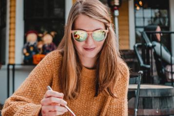 Woman wearing sunglasses eating at a table