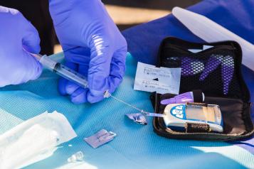 Person using disposable syringe putting a specimen on a glucose meter