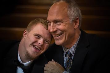 Older man with arm around younger man both smiling