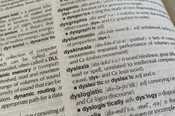 Open page of a dictionary showing the word and meaning of dyslexia